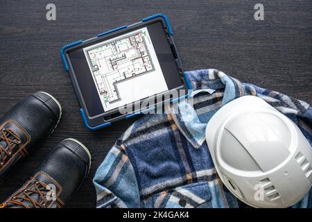 Digital tablet with layout and worker clothes, top view. Stock Photo