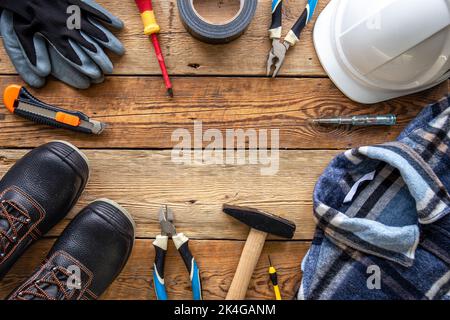 Set of repair tools and work uniform on wooden background, flat lay. Stock Photo