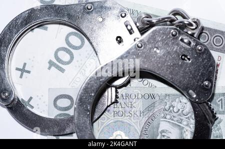 Police handcuffs and banknotes in Polish currency. The concept of economic crime in Poland. Banknotes of Polish zlotys. Stock Photo