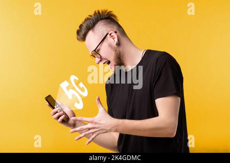 5G network. Wireless Internet. Mobile telecommunication. ICT digital future. Cellular technology. Excited guy holding smartphone with icon hologram is Stock Photo