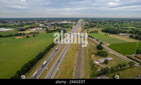 Brecht, Belgium, 6th of July, 2022, Panoramic aerial drone view of wind farm or wind park, with high wind turbines for generation electricity with the motorway with few cars and railroad next to it, near the exit of Brecht in Belgium, Europe. High quality photo Stock Photo