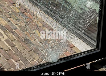 Close up view of cracks in a pane of toughened glass in a door after being struck by an object. No people. Stock Photo