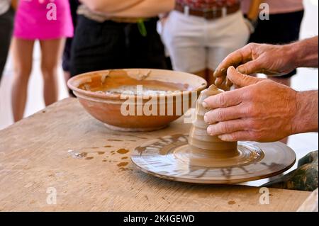 Potter making a vase on a potter's wheel using wet clay Stock Photo