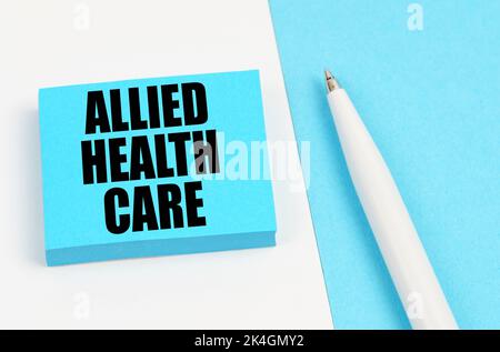 Medical concept. On a white and blue surface, a pen and blue stickers with the inscription - Allied Health Care Stock Photo