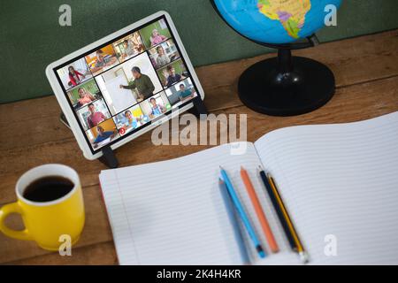 Biracial male teacher with smiling diverse elementary school pupils on tablet screen. communication technology and online education, digital composite Stock Photo