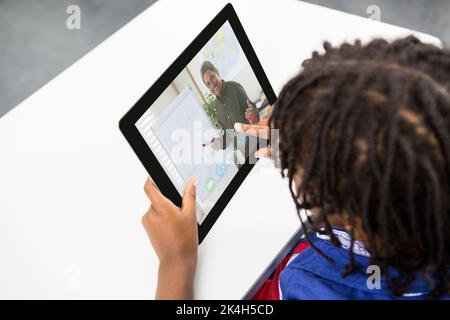 Male student having a video call with male teacher on digital tablet at school. distance learning online education concept Stock Photo
