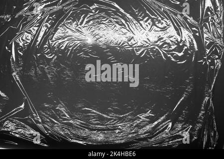 Reflecting light and shadow on creases and folds in plastic sheeting. monochrome light and texture, abstract background image. Stock Photo