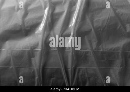 Reflecting light and shadow on creases and folds in plastic sheeting. monochrome light and texture, abstract background image. Stock Photo