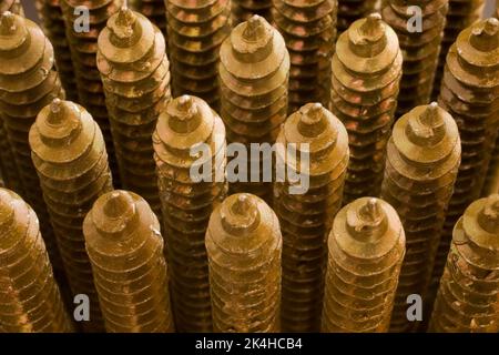 Close-up of neatly arranged upright brass screws. Stock Photo