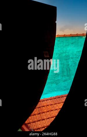Hatch cover from an old fishing boat is cracked open showing sky, and another colorful building, Abstract, shape and color. Stock Photo