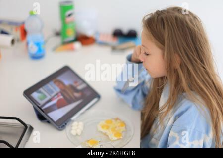 child enjoys a healthy natural drink while having breakfast in kitchen at home. Proper nutrition for children Stock Photo