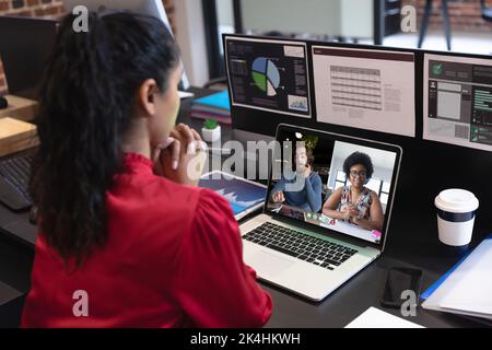 Caucasian woman in office having video call with diverse colleagues displayed on laptop screen. social distancing communication technology workplace d Stock Photo
