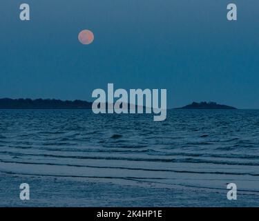 Super Moon Rising Over the Sea with Island in the Background Stock Photo
