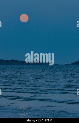 Super Moon Rising Over the Sea with Island in the Background Stock Photo