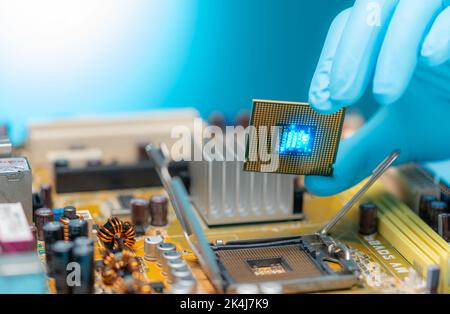 Electronic engineer hand putting computer chip on socket. Chipset on electronic circuit board of PC mother board. CPU chip. Electronic components. Stock Photo