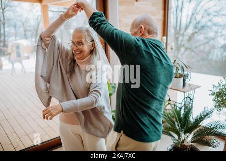 Senior couple in love dancing together in their modern living room. Stock Photo