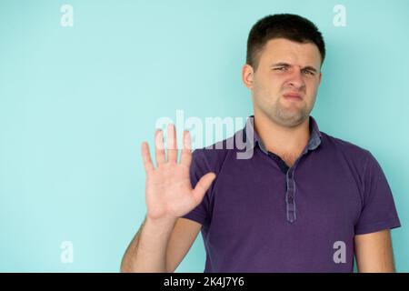 Protesting gesture. Dissatisfied man. No way. Disappointed guy holding forbidden hand up expressing displeased emotion isolated blue copy space. Stock Photo