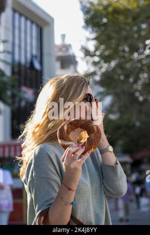 Blonde woman keep bagel on her hand and smiling. Street food, take away. Istanbul turkey Stock Photo