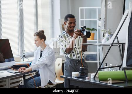 Portrait of smiling black man working in photo studio and taking product images Stock Photo