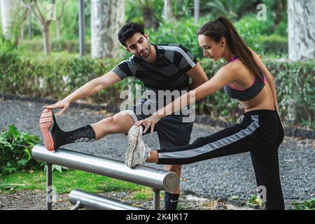 Active couple of young people practicing fitness stretching legs outdoors in the park relaxing and exercising together - sport and healthy active life Stock Photo