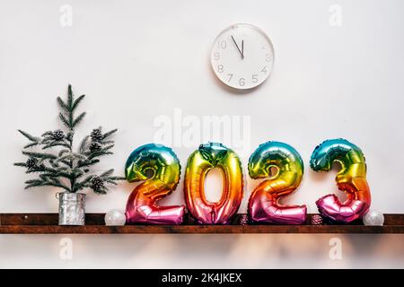 Christmas tree, white clock, decorations and air balloons in numbers shape in front of wooden wall Stock Photo