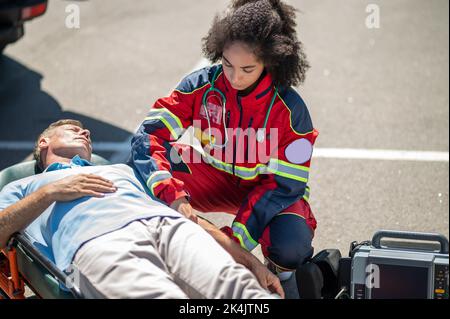 EMT strapping the patient to the stretcher Stock Photo