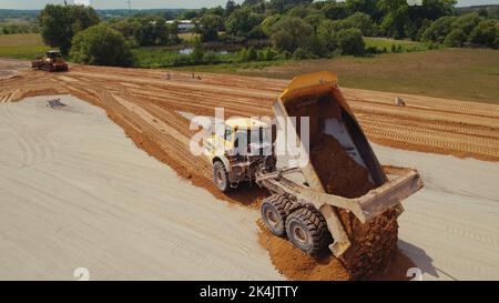 Industrial dumper truck working on a highway construction site, unloading soil. Bulldozer leveling the ground. Warsaw, Poland. . High quality photo Stock Photo