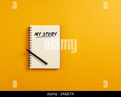 Notepad and black pen on yellow background with the handwritten word my story. Telling about yourself and biography concept. Stock Photo