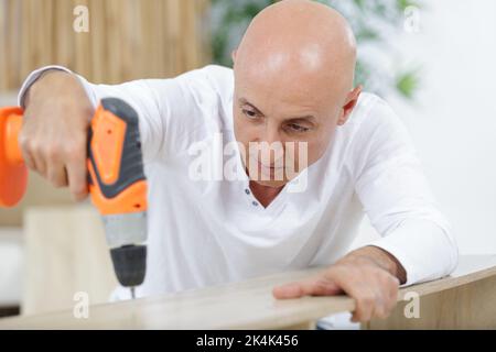 carpenter makes a hole in old wooden door Stock Photo