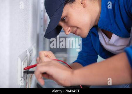 happy female builder fixing socket indoors Stock Photo