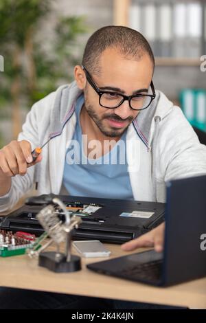 young energetic male tech or engineer repairs laptop Stock Photo