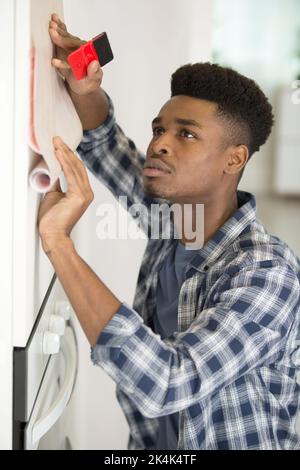 man revamping kitchen unit with adhesive material Stock Photo