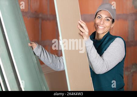 female worker carry styrofoam sheet insulation at construction site Stock Photo