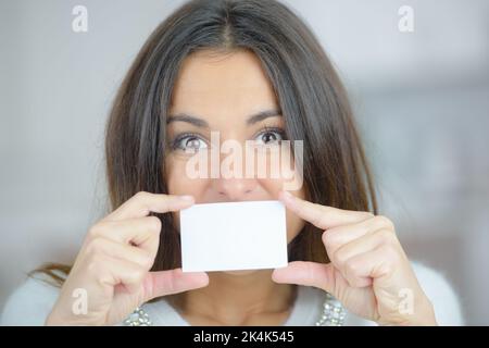 Lady holding blank card over her mouth Stock Photo