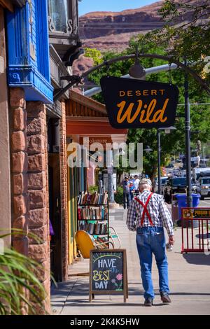 An old man in a check shirt and red bracers walks along the main street on a hot day in Moab Utah USA Stock Photo