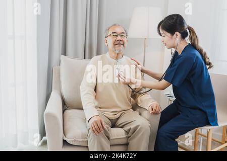 Asian nurse, doctor woman assisting checking heart rate stethoscope of Senior Asian patient man Stock Photo