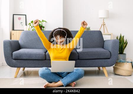 Excited young african american woman celebrating success working on laptop Stock Photo