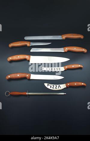 Different kitchen knives a on black surface. Includes carving, paring, and utility knives Stock Photo