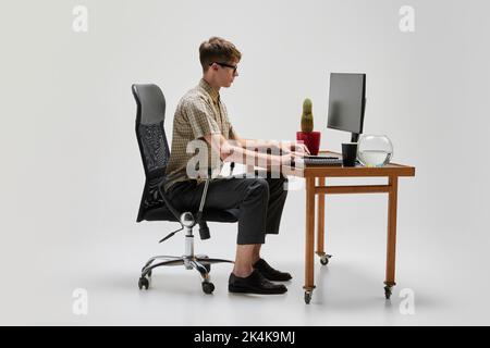 Young programmer. Portrait of smart and serious student sitting at computer desk and studying. Studying, education, youth, remote workplace concept Stock Photo