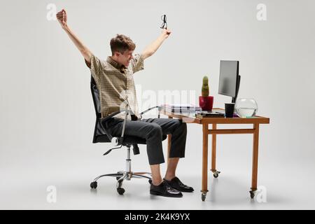 Happy and cheerful student sitting at computer desk and studying. Business, career, home education, youth, remote workplace concept Stock Photo