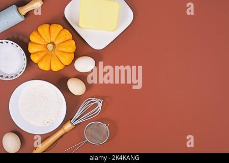 Ingredients and baking tools for pumpkin pie on brown background with copy space Stock Photo