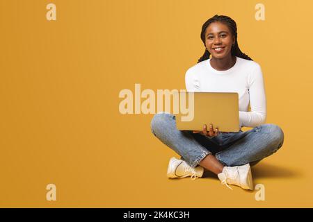 Cheerful attractive african-american female employee or student using laptop, confident young multiracial business woman looking at the camera and smiling Stock Photo