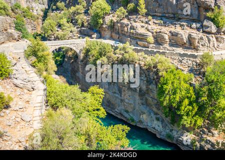 Ancient arch bridge over the Koprucay river gorge in Koprulu national Park in Turkey. Panoramic scenic view of the canyon and blue stormy mountain Stock Photo