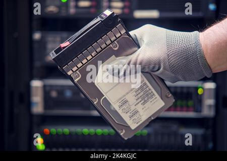 A hard disk for a raid in the hands of a man at a data storage server, close-up Stock Photo