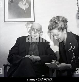 1965, historical, a elderly man sitting in a chair in an old peoples home being interviewed by a female journalist who is taking notes, Scotland, UK. Stock Photo