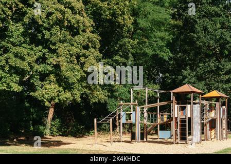 Children's wooden playground recreation area at public park. Children's playground, swing, slide, stairs. A place for children to play. Gymnastics Stock Photo