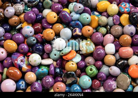 A background of colourful ceramic glazed beads. Traditional African beads for ethnic jewelery and souvenirs. Overhead view. Stock Photo