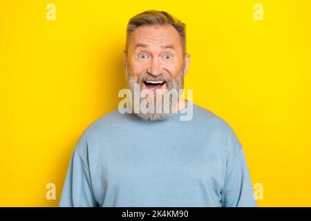 Photo of cute impressed man pensioner dressed blue pullover smiling open mouth isolated yellow color background Stock Photo