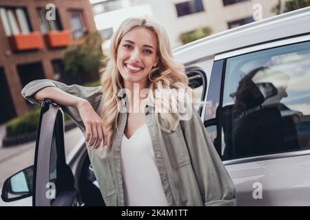 Portrait of pretty positive lady toothy smile good mood standing near car open door outside Stock Photo