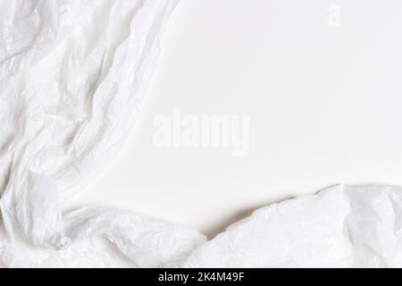White plastic wrap background. Crumpled wrinkled plastic cellophane on blank white background. Reflecting light and shadow on creases and folds in Stock Photo